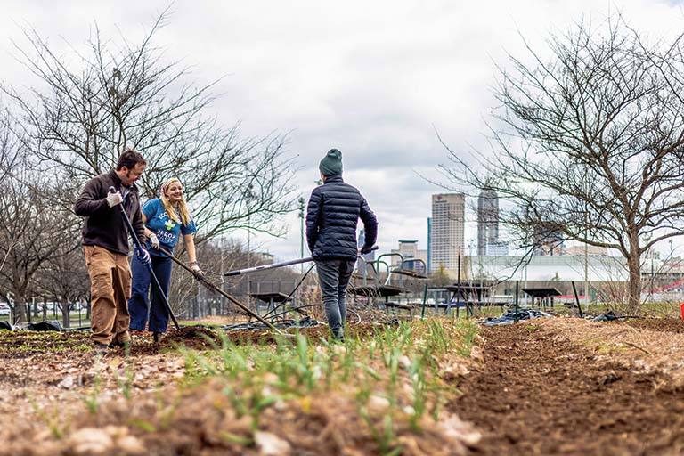 Students work in field with Indy skyline in back.